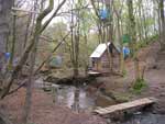 anti road protest camp at Bilston Glen, near Edinburgh, Scotland. photo of tree houses by a stream running through the camp.